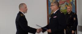 Na zdjęciu Kujawsko-Pomorski Komendant Wojewódzki st. bryg. Jacek Kaczmarek wręcza pochwałę mł. asp. Rafałowi Raczkowskiemu, otrzymaną za nienaganną postawę i ofiarne niesienie pomocy. 