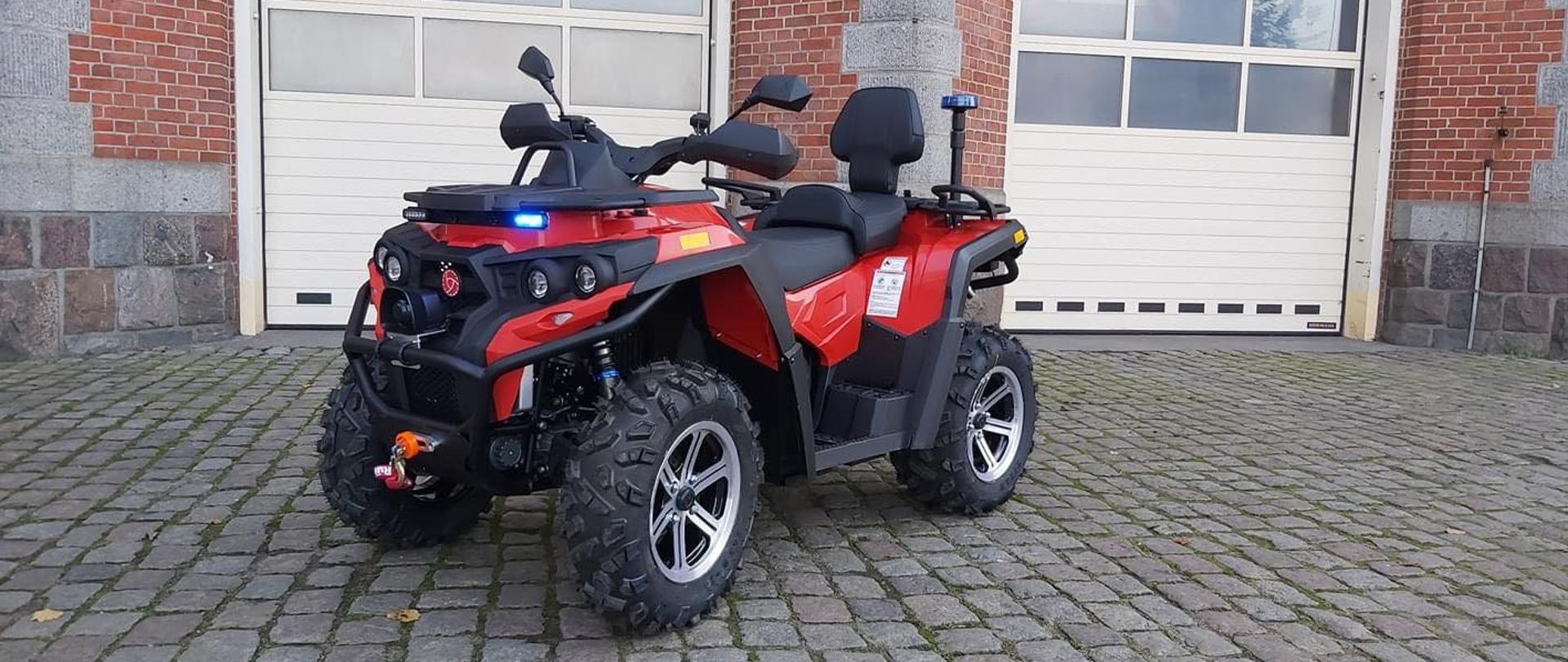 Czerwony quad ze świtałami do jazdy alarmowej na tle garaży jrg5 w szczecinie