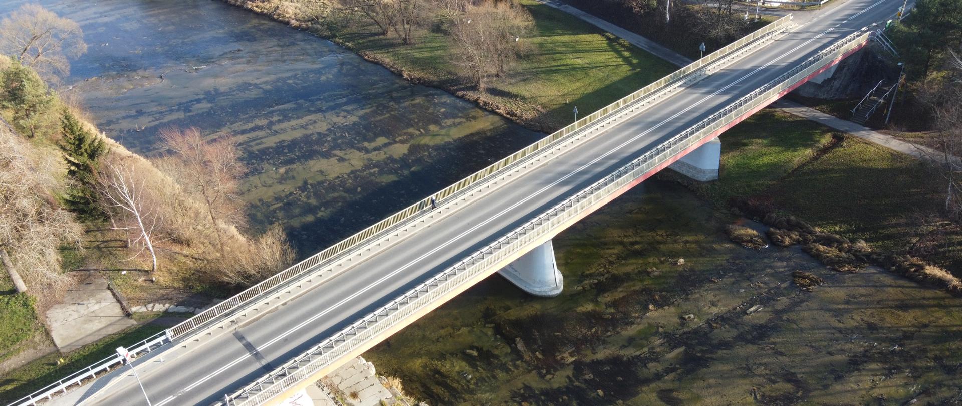Na zdjęciu widać most nad rzeką. Jest Ładna pogoda. Nie widać samochodów.
