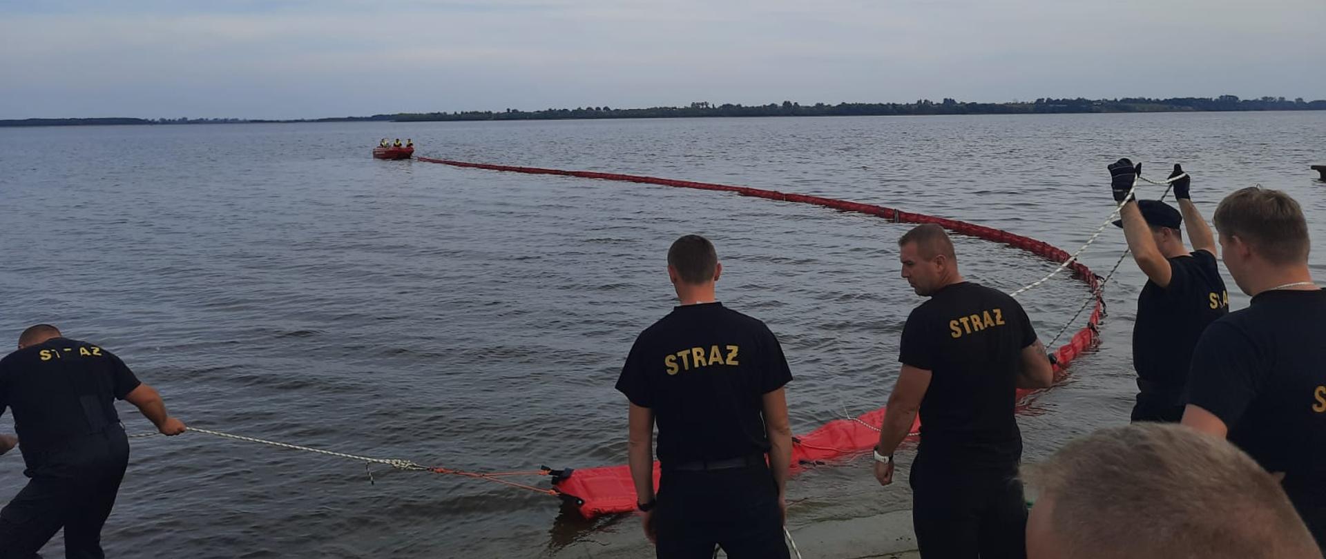 Strażacy rozkładający zaporę na zbiorniku wodnym