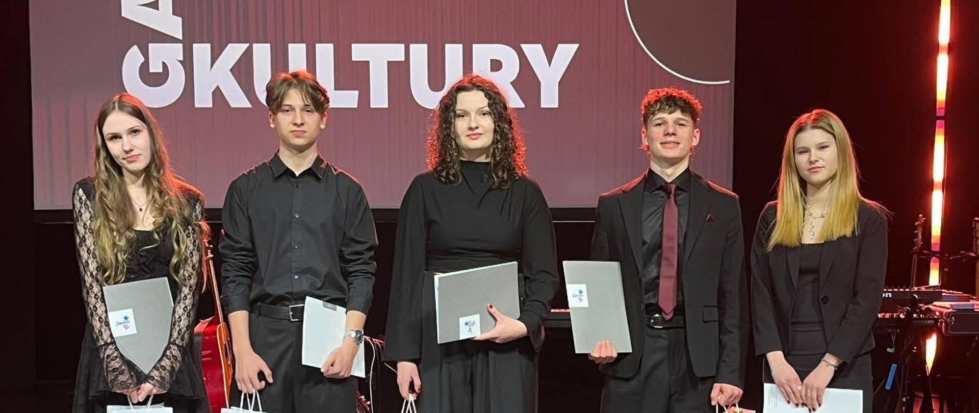 Zdjęcie przedstawia stypendystów Prezydenta Miasta Stargard za rok 2025, stojących na scenie Stargardzkiego Centrum Kultury.