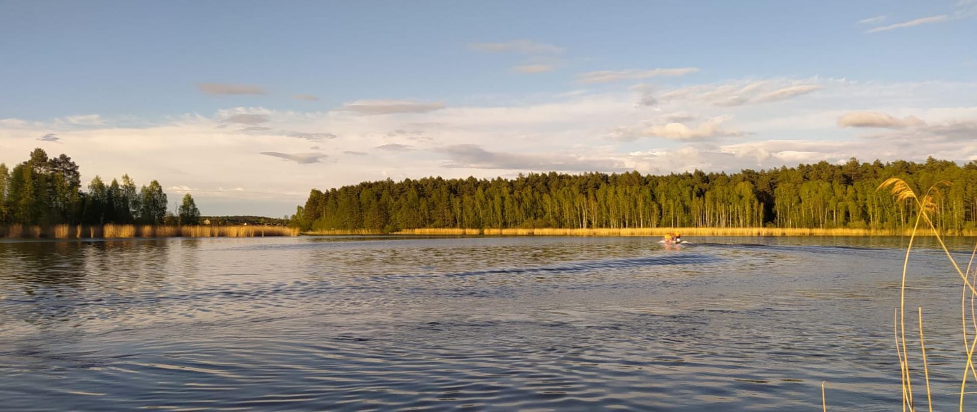 Widok jeziora i łodzi strażackiej.