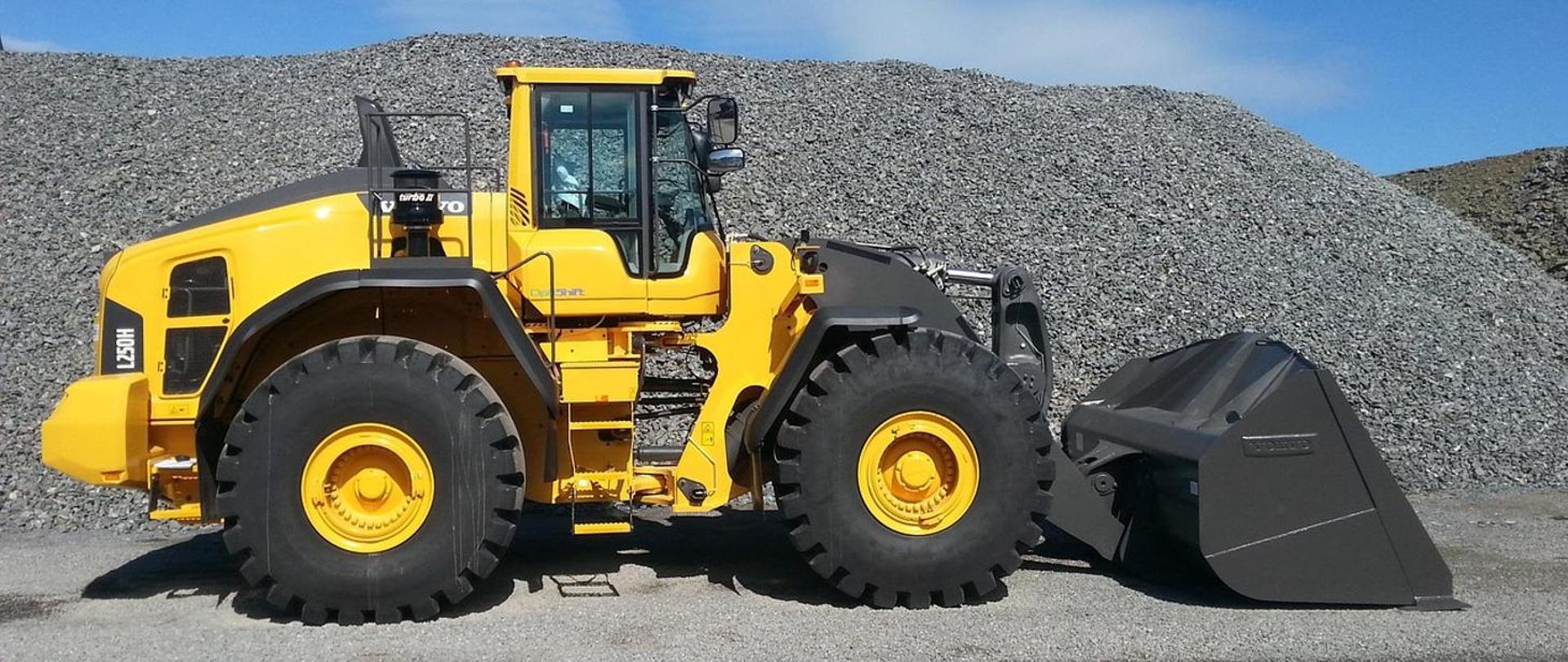 obraz przedstawia spycharkę na tle kopalni odkrywkowej