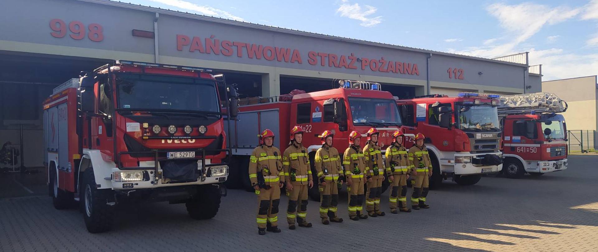 78. rocznica wybuchu Powstania Warszawskiego - na zdjęciu strażacy PSP w ubraniu specjalnym na placu przed strażnicą na zbiórce w szeregu przed czerwonymi samochodami strażackmi