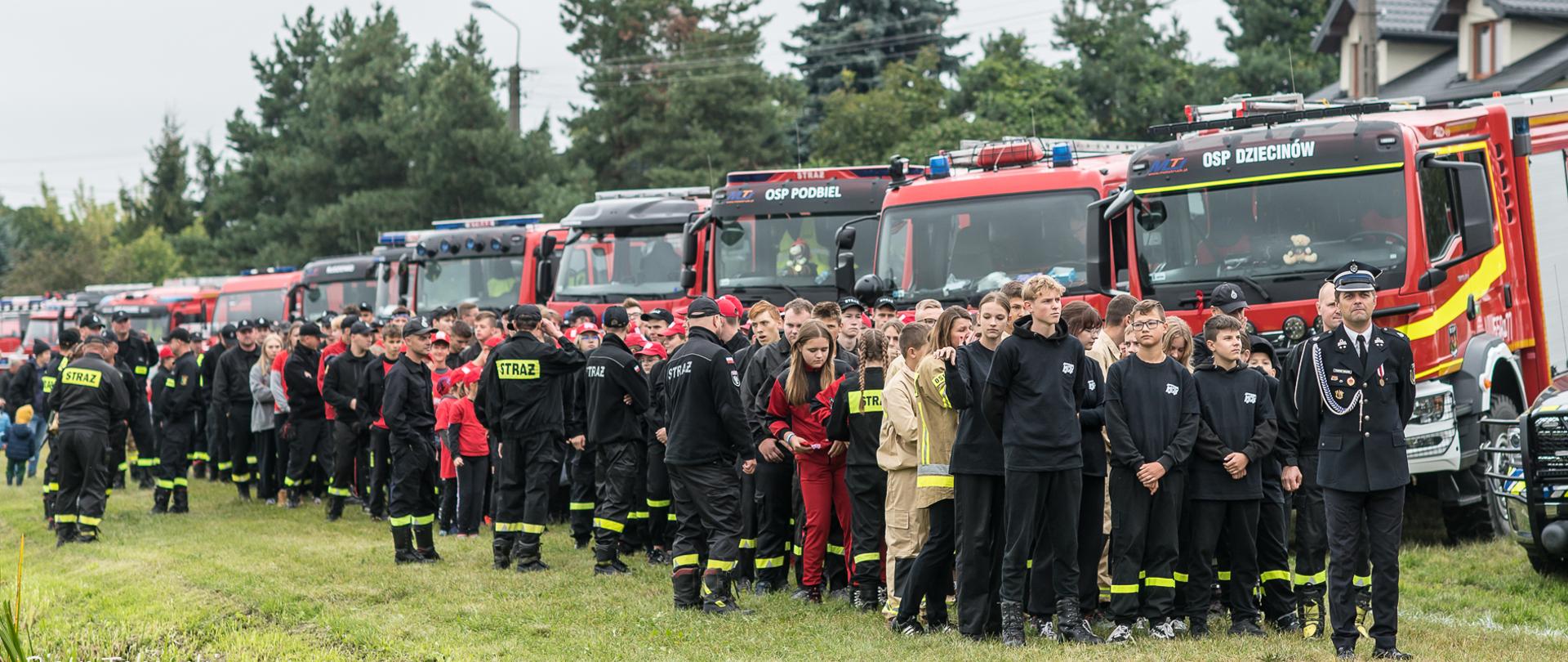Na zdjęciu uczestnicy zawodów młodzieżowych drużyn pożarniczych na tle pojazdów gaśniczych