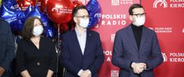 Premier Morawiecki i minister Buda stoją na tle ścianki Polskiego Radia