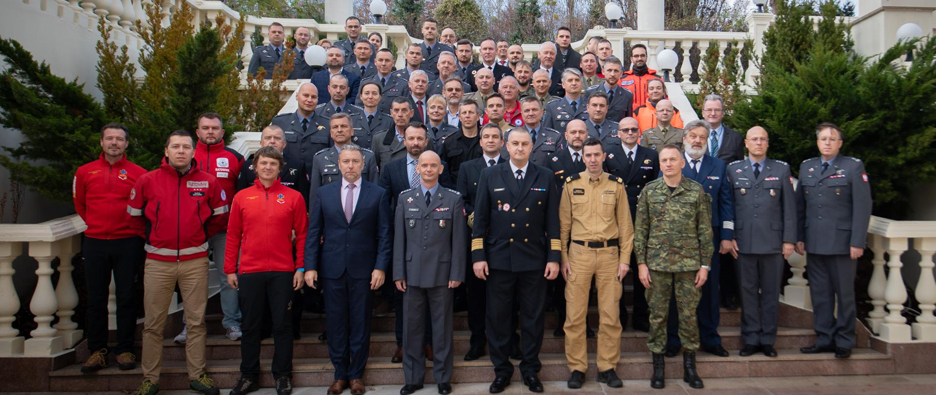 Zdjęcie grupowe uczestników konferencji na schodach przed budynkiem. 