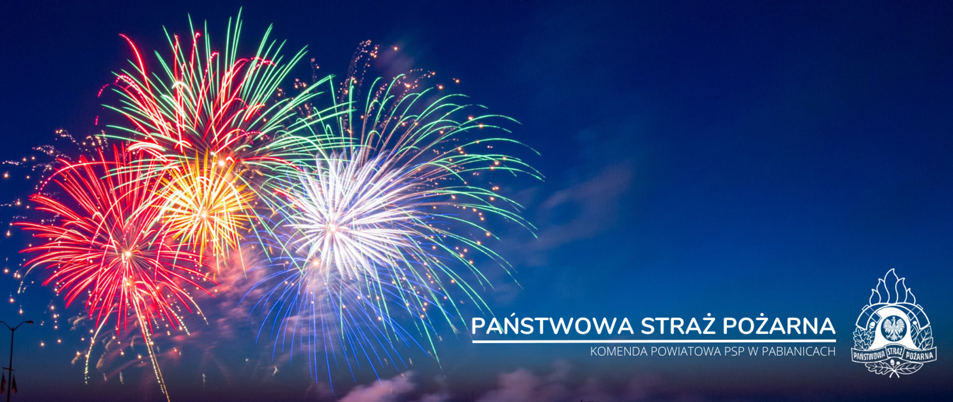Grafika przedstawia rozbłysk fajerwerków na tle nocnego nieba. W prawym dolnym rogu napis "Państwowa Straż Pożarna, Komenda Powiatowa PSP w Pabianicach" oraz logo PSP w wersji białej.