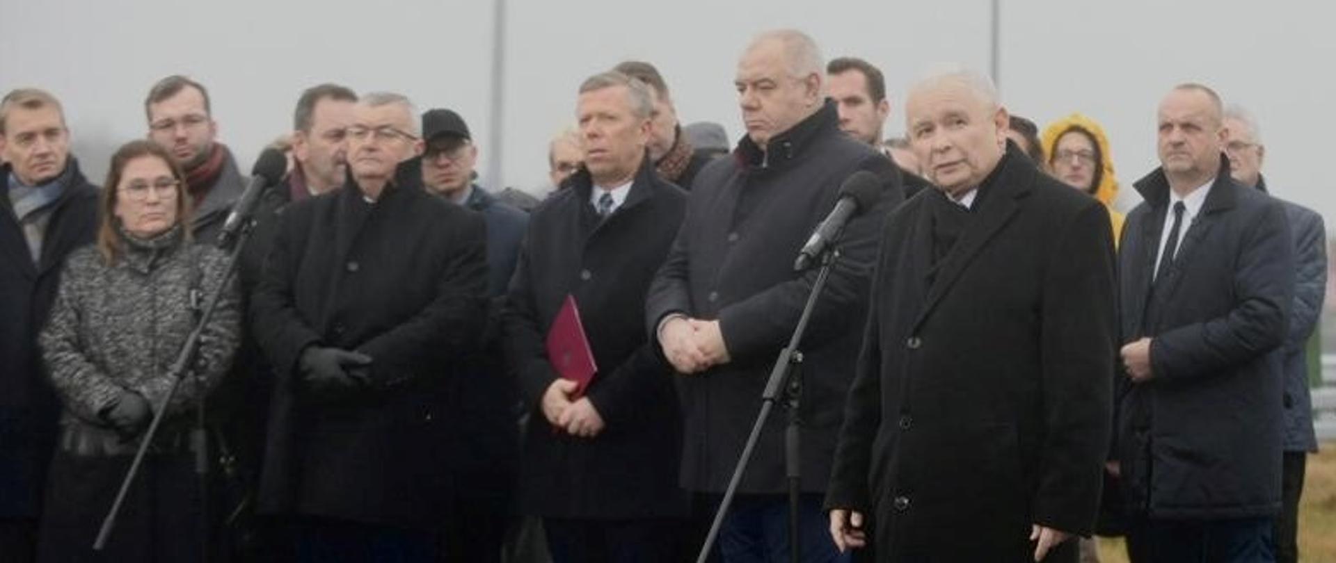 Na zdjęciu grupa kilkudziesięciu ludzi stoi na nowej drodze ekspresowej. Do mikrofonu przemawia premier Jarosław Kaczyński.