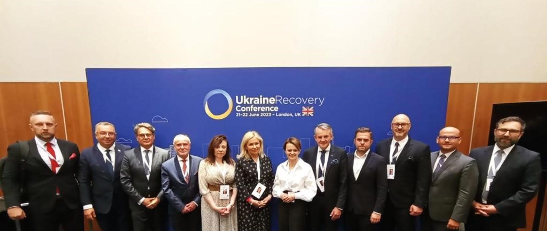 Kilkanaście osób stoi obok siebie w rzędzie.