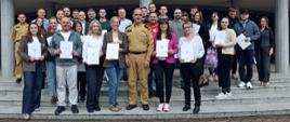 Pamiątkowe zdjęcie grupowe uczestników szkolenia inspektorów ochrony przeciwpożarowej (29 osób) w towarzystwie Zastępcy Komendanta Centralnej Szkoły PSP, funkcjonariusza CS PSP oraz kobiety