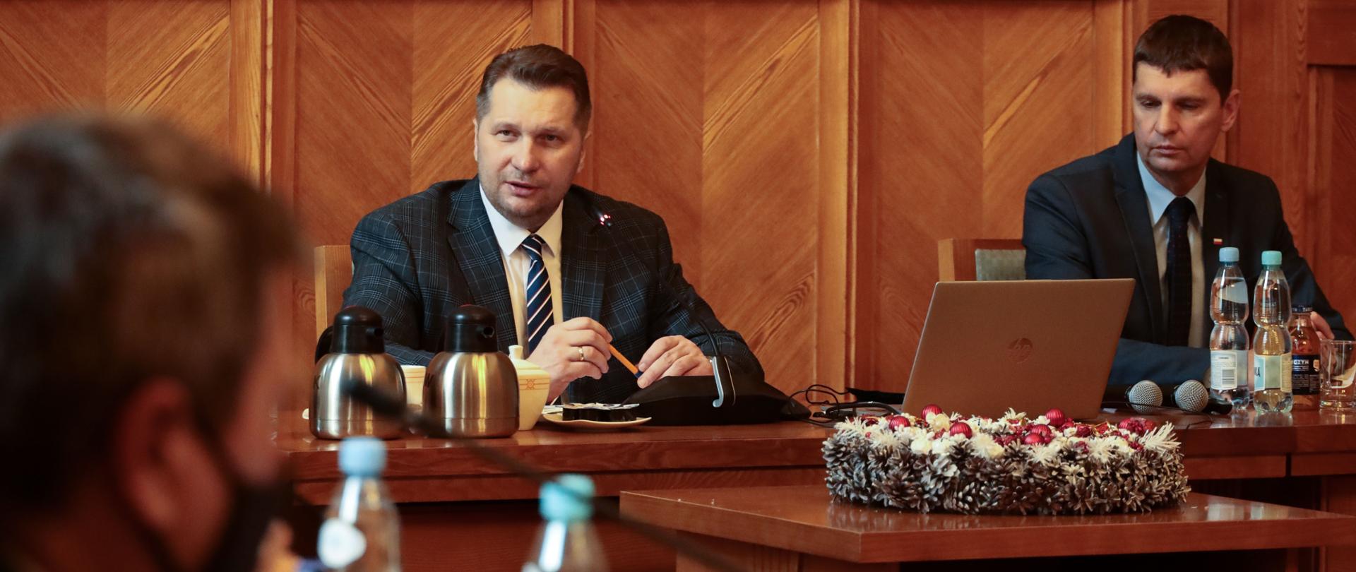 Spotkanie z członkami Zespołu ds. statusu zawodowego nauczycieli - samorządowcy, minister Przemysław Czarnek oraz wiceminister Dariusz Piontkowski podczas obrad, siedzą przy stole.