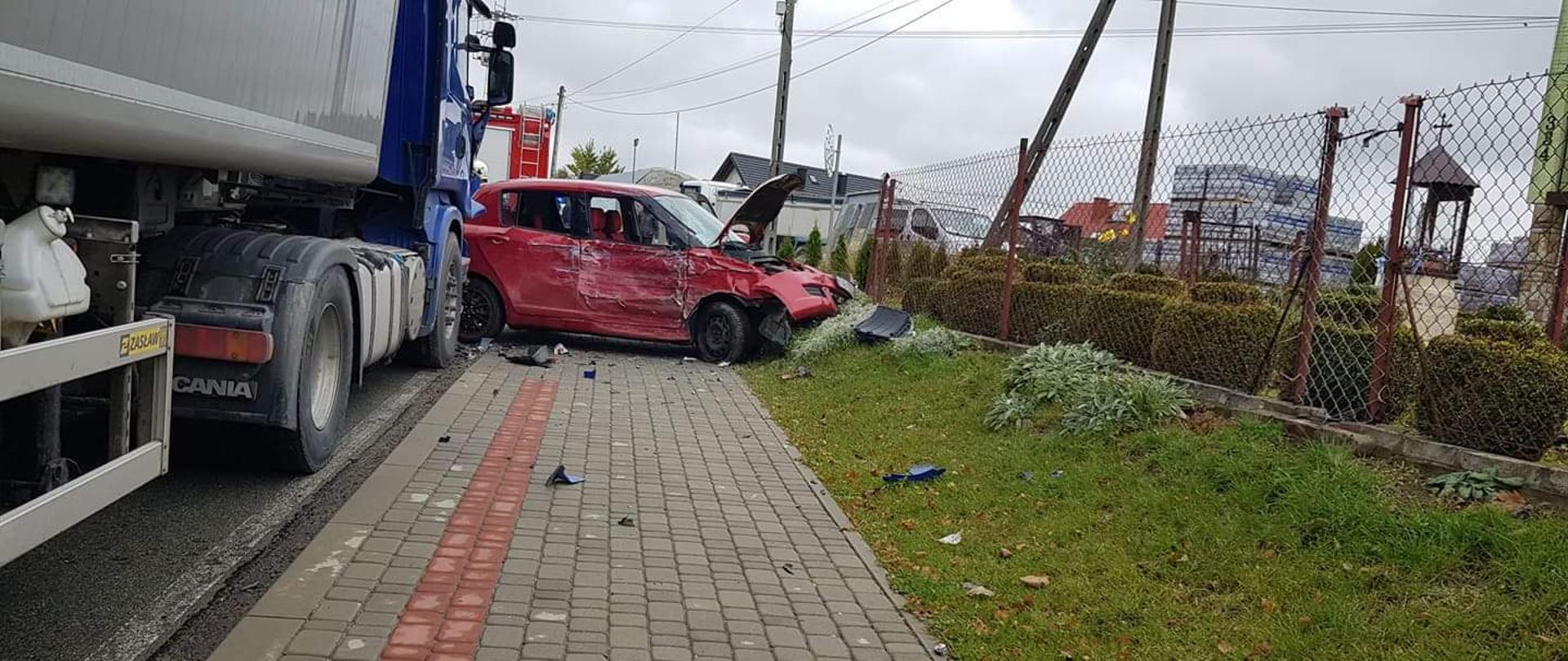 Samochód osobowy na chodniku a ciężarowy na drodze.