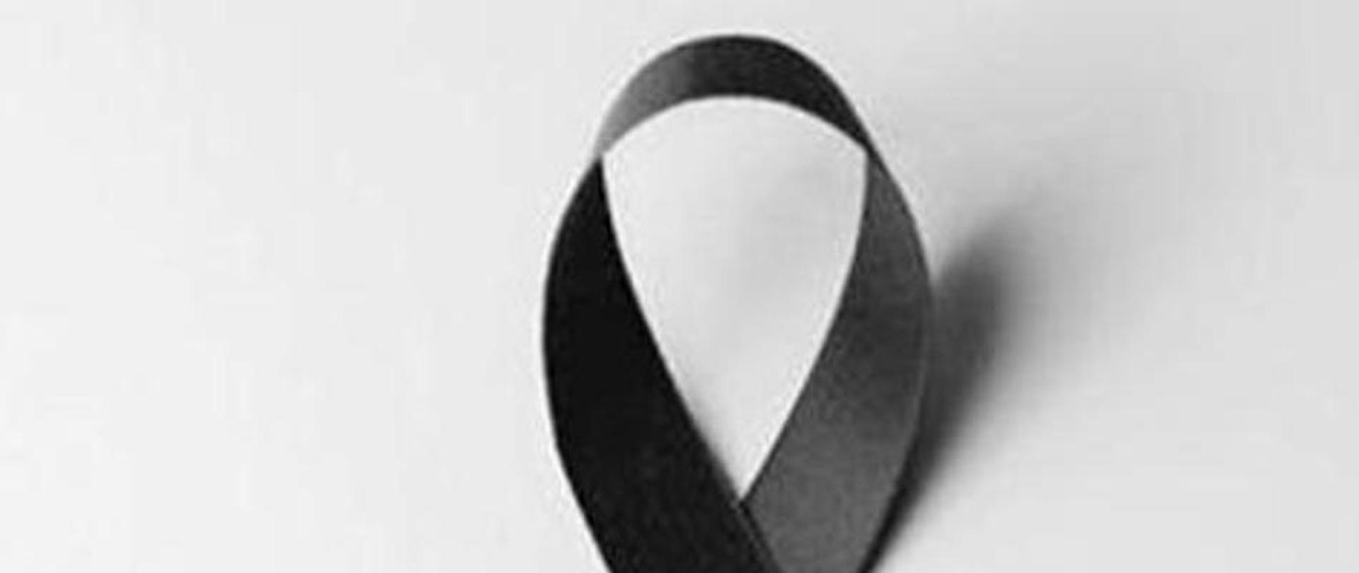 Zdjęcie przedstawia czarną żałobną kokardę na białym tle