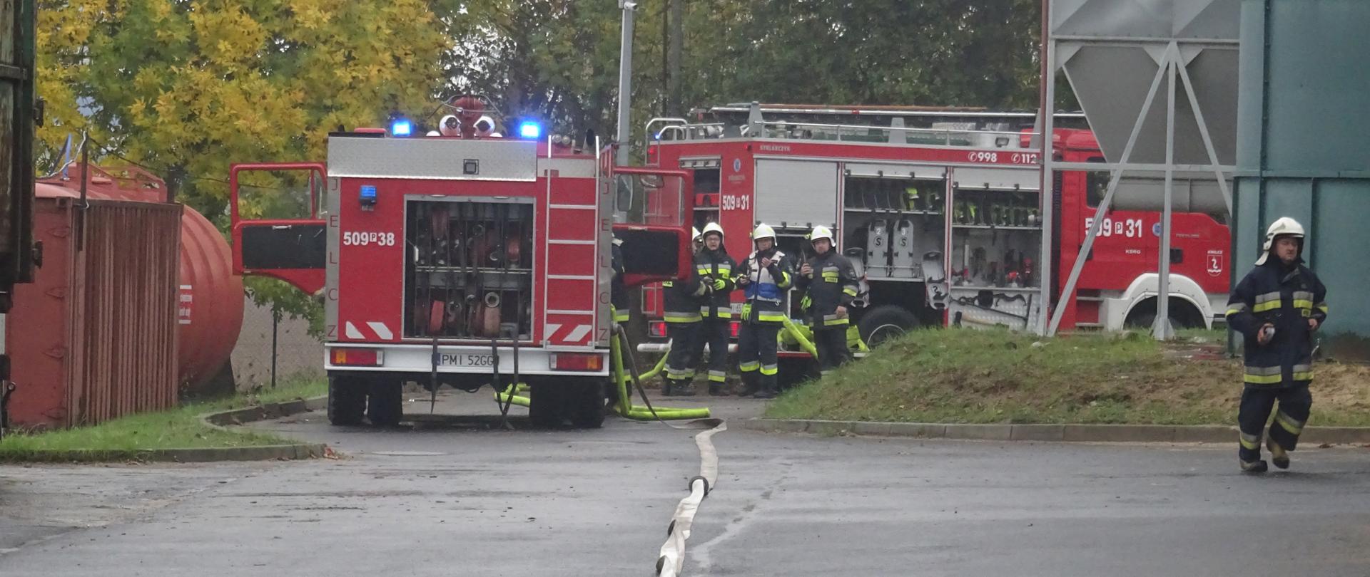 Zdjęcie przedstawia wozy pożarnicze wraz ze strażakami.