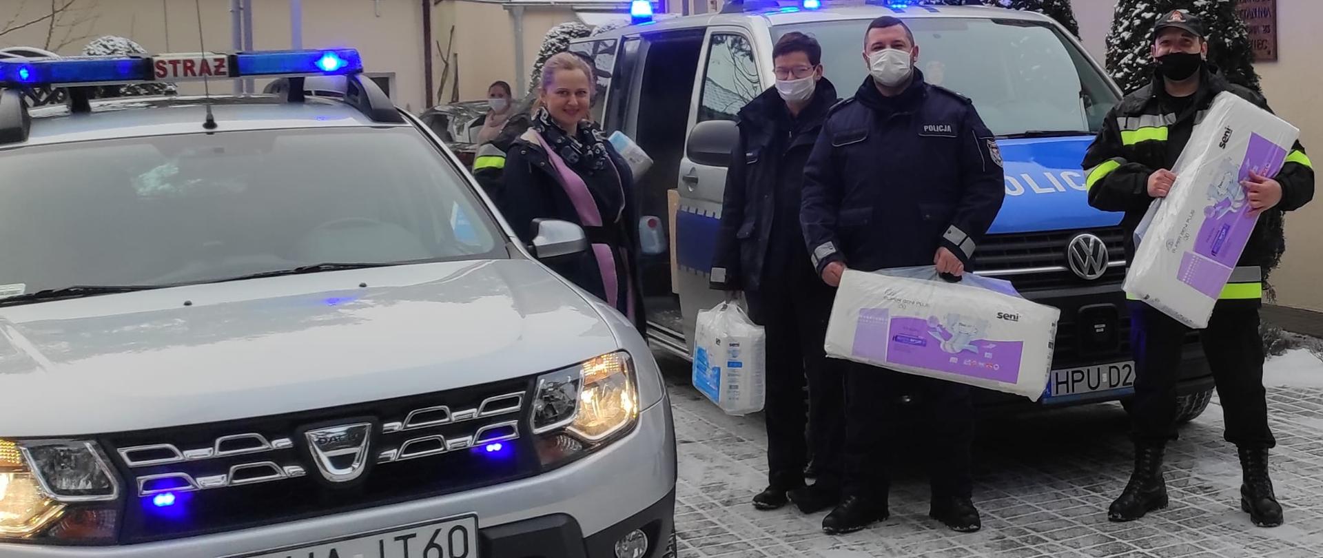 Na zdjęciu widać strażaków i policjantów przekazujących dary dla hospicjum