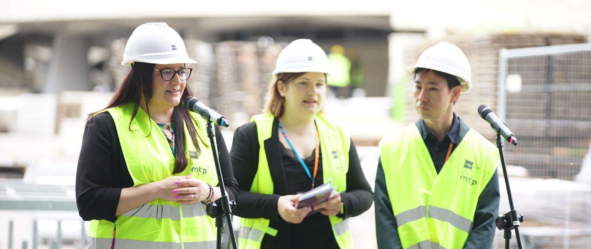 uczestnicy konferencji stoją przed mikrofonami