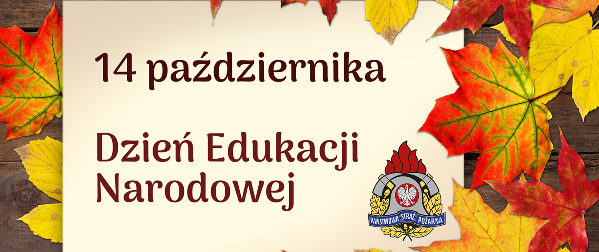 Grafika z napisem „14 października – Dzień Edukacji Narodowej”. Tło w jesiennych barwach z kolorowymi liśćmi klonu i drewnianą fakturą. W prawym dolnym rogu znajduje się logo Państwowej Straży Pożarnej.