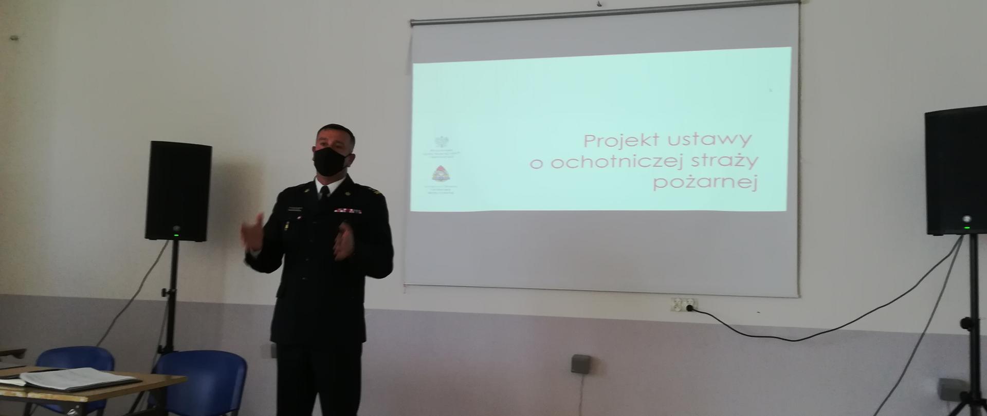 Zdjęcie zrobione wewnątrz świetlicy osp, na zdjęciu scena na której komendant powiatowy psp w Lubaczowie, przedstawia projekt ustawy o osp, 