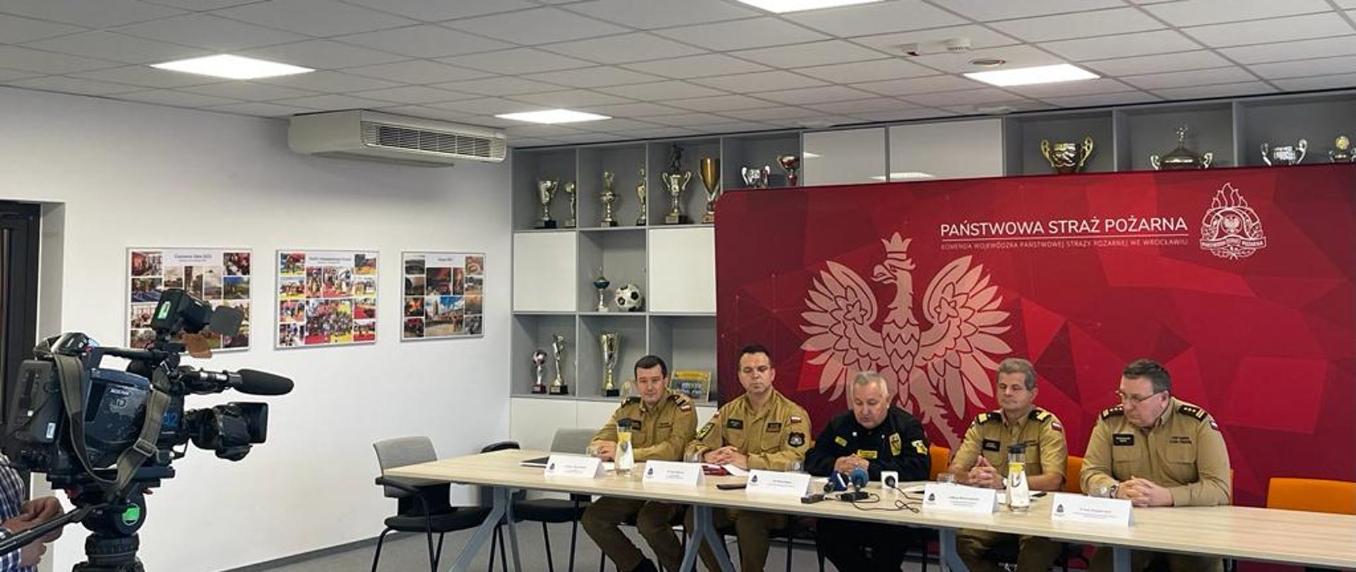 Uczestnicy konferencji prasowej siedzący w umundurowaniu na sali. 