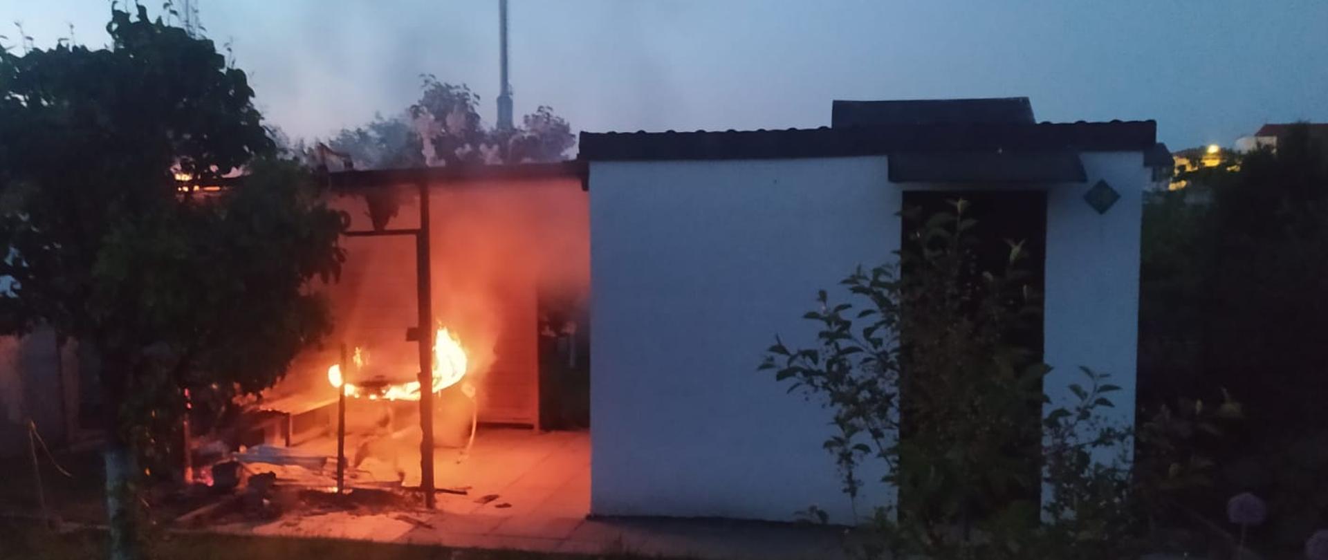 świt, na zdjęciu widać altanę murowaną i obok palącą się drewnianą przybudówkę.