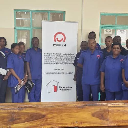 Grupa osób pozuje do zdjęcia przed kliniką, są ubrani w stroje pracowników medyczynych