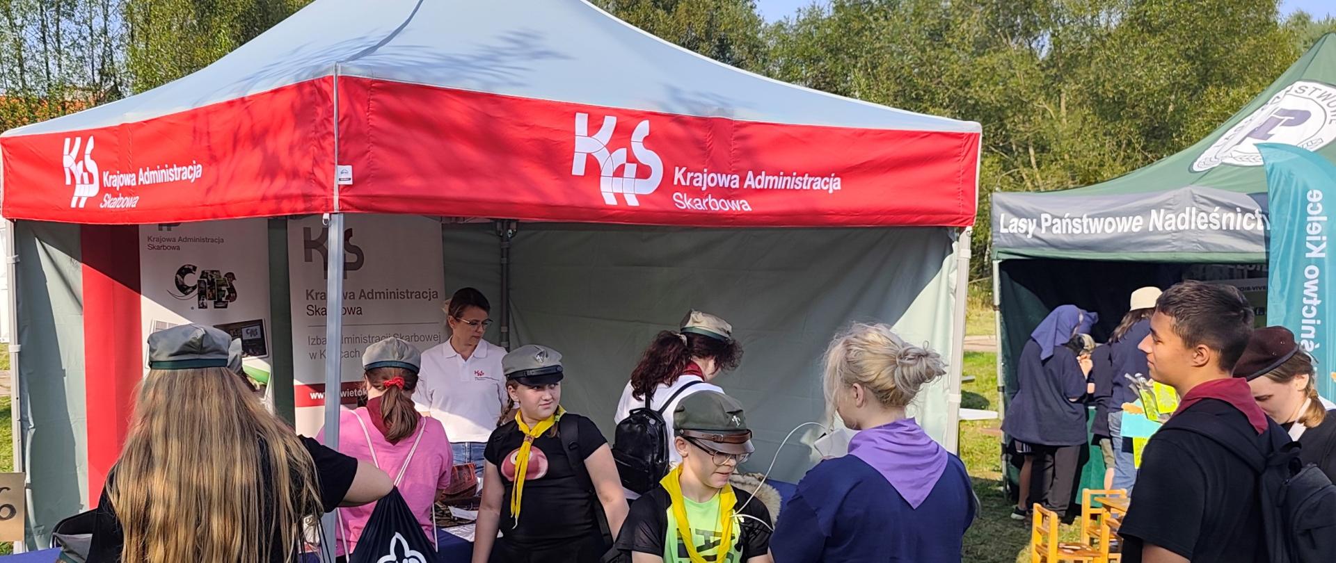 Grupa harcerzy stoi przy namiocie Krajowej Administracji Skarbowej