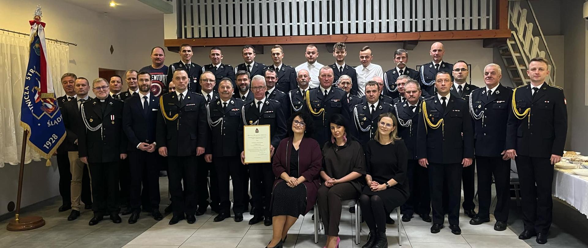 Pamiątkowe zdjęcie wykonane po uroczystości oficjalnego wręczenia decyzji włączającej OSP Ślądkowice do krajowego systemu ratowniczo-gaśniczego. Na zdjęciu członkowie jednostki OSP i goście.
