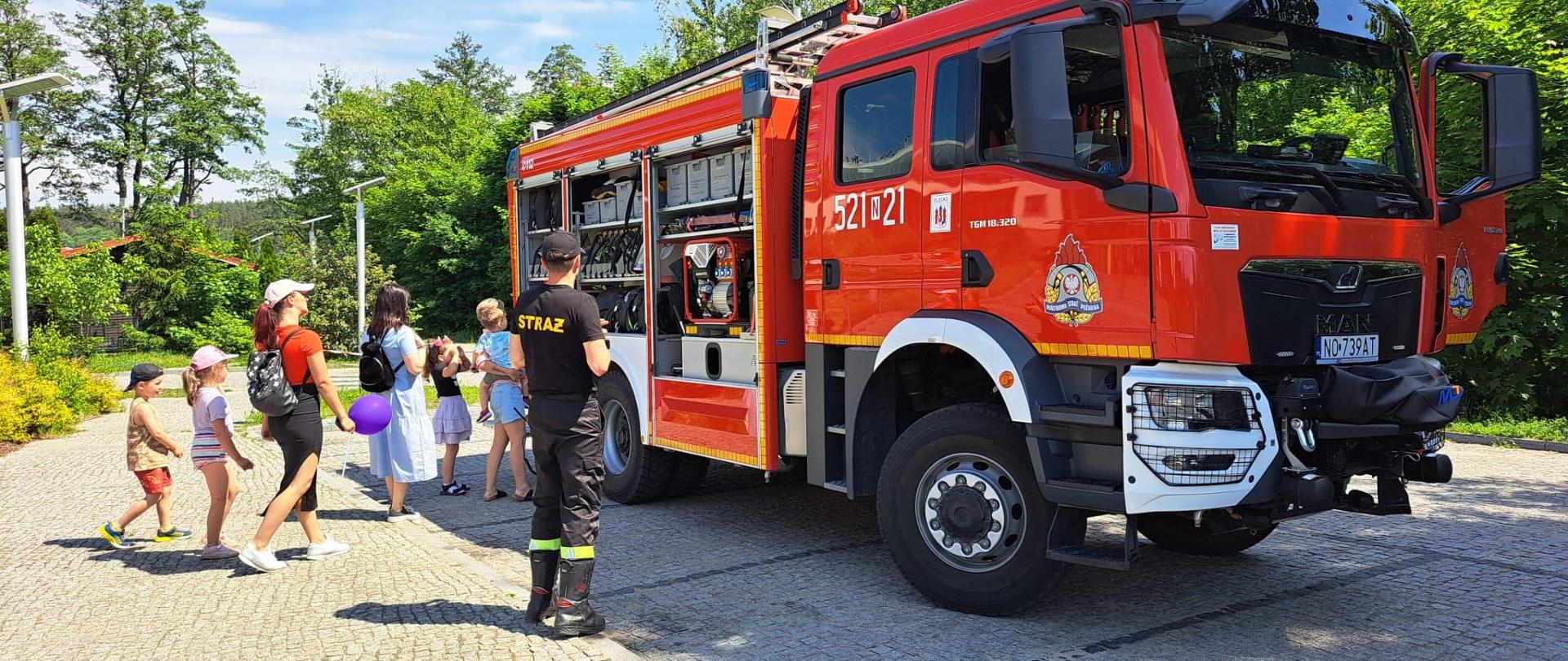 Strażak, samochód gaśniczy oraz widzowie