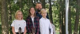 Uczniowie z klasy gitary Witolda Kozakowskiego (Natalia Skrzydło, Dobrawa Wers-Skawina i Cezary Petelski) stojący na tle drzew i trzymający gitary wraz z upominkami
