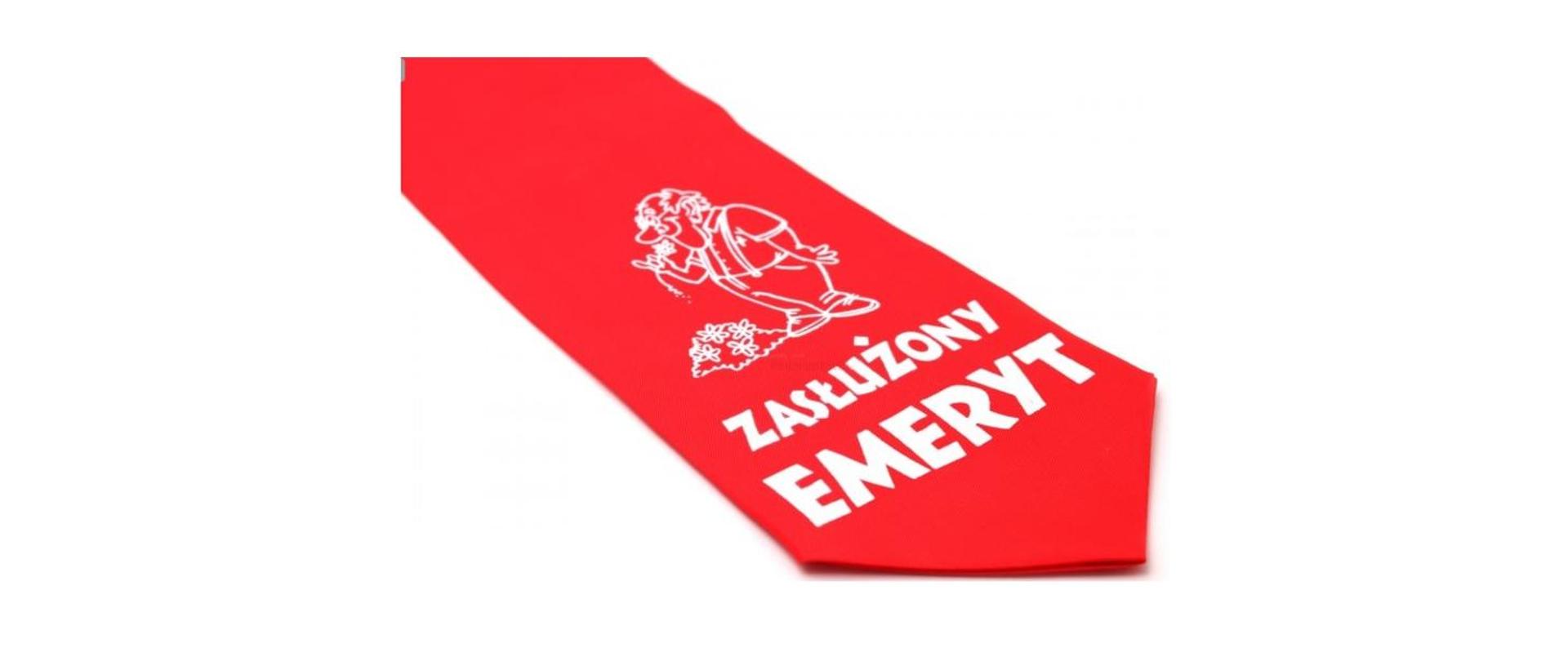 Na zdjęciu widoczny jest czerwony krawat leżący na białym tle. W górnej części, tuż pod węzłem, znajduje się biały rysunek starszego, uśmiechniętego mężczyzny w charakterystycznej pozie, trzymającego coś w ręku. Poniżej, na środku krawata, widnieje biały napis składający się z dwóch słów: "ZASŁUŻONY" i "EMERYT".