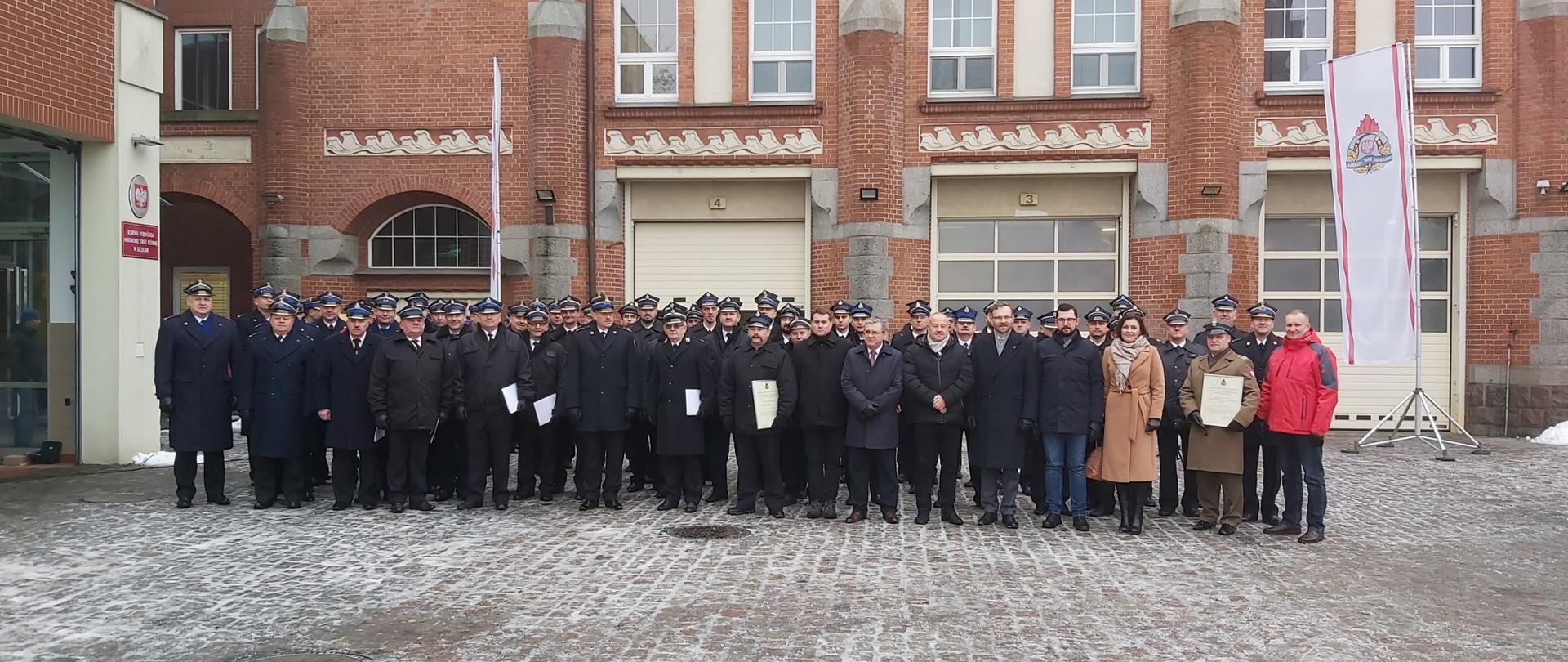 na zdjęciu widać przedstawicieli Ochotniczych Straży Pożarnych, Wojskowej Straży Pożarnej, Komendantów Miejskich i Powiatowych Państwowej Straży Pożarnej oraz zaproszonych gości pozujących do wspólnego zdjęcia przed budynkiem Komendy Wojewódzkiej PSP w Szczecinie.