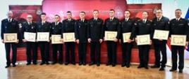 Kolorowa fotografia wykonana w Sali konferencyjnej KW PSP w Rzeszowie. Przedstawia strażaków PSP i OSP z dyplomami za akcję ratowniczą związana z uratowaniem przysypanego mężczyzny.