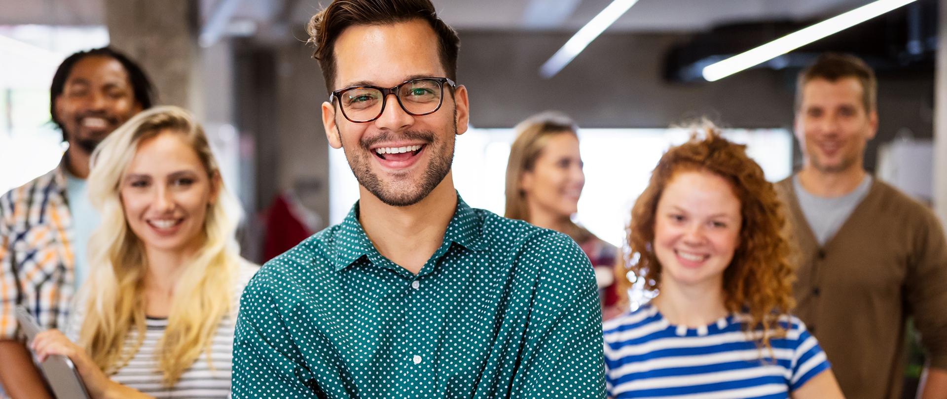 Zdjęcie przedstawia grupę młodych uśmiechniętych osób, kobiet i mężczyzn