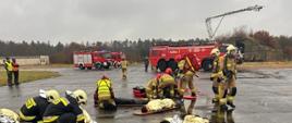 Strażacy udzielający pomocy osobom poszkodowanym (pozorantom ćwiczeń)