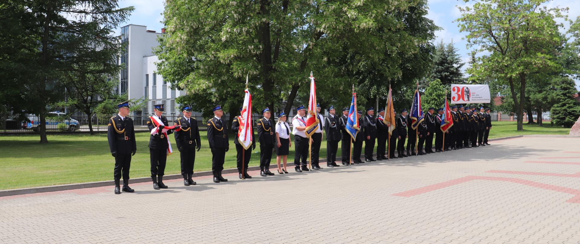 Poczet flagowy oraz poczty sztandarowe stoją w ugrupowaniu na placu.