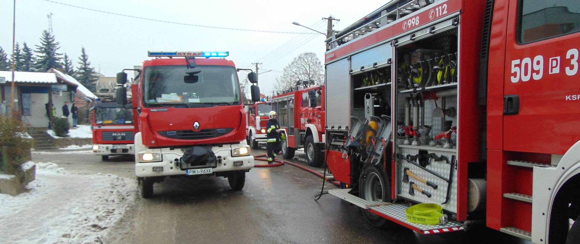 Zdjęcie przedstawia kilka pojazdów pożarniczych, ustawionych na drodze w kolumnie.