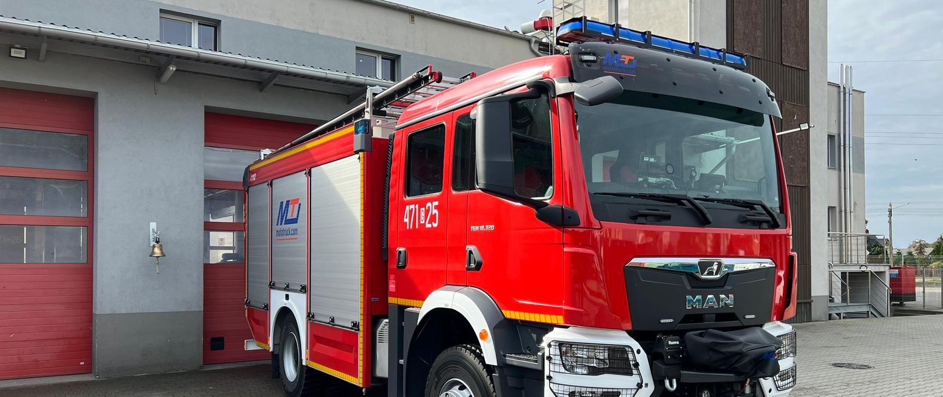 Nowy ciężki samochód ratowniczo-gaśniczy MAN TGM przed budynkiem komendy, widok od przodu z prawej strony