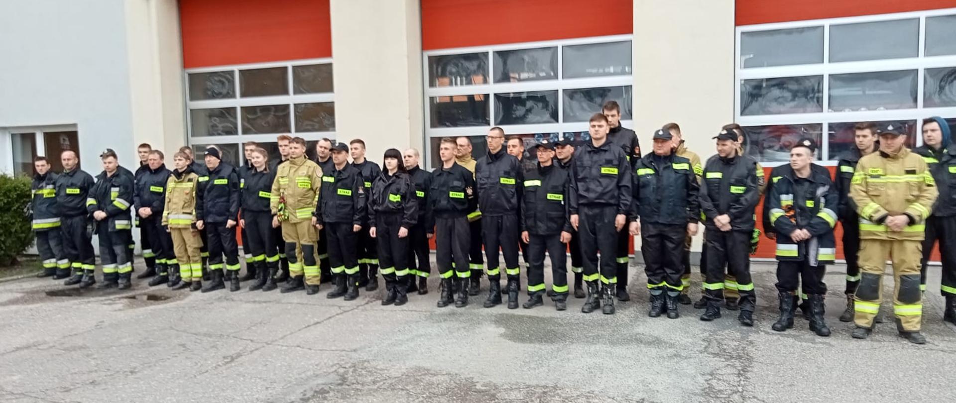 druhny i druhowie OSP w dwuszeregu przed bramami wjazdowymi Komendy PSP w Kozienicach