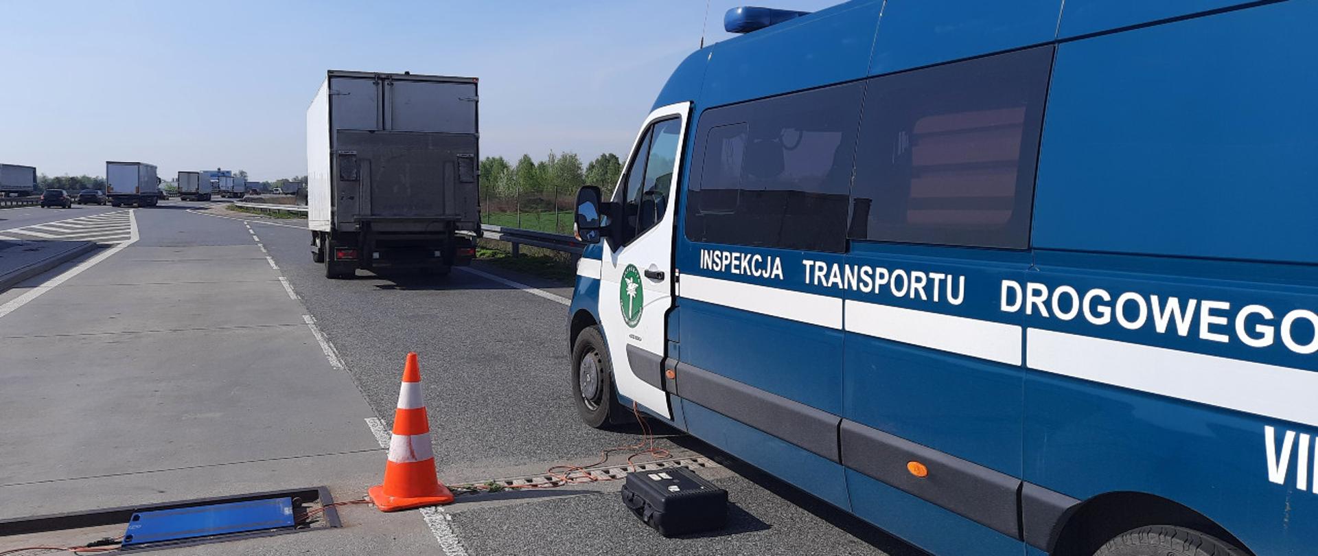 Na pierwszym planie (od lewej): rozłożone wagi inspekcyjne w punkcie kontrolnym przy drodze ekspresowej i stojący obok oznakowany furgon mazowieckiej Inspekcji Transportu Drogowego. W tle: przed furgonem ITD stoi kontrolowany, znacznie przeładowany pojazd dostawczy.