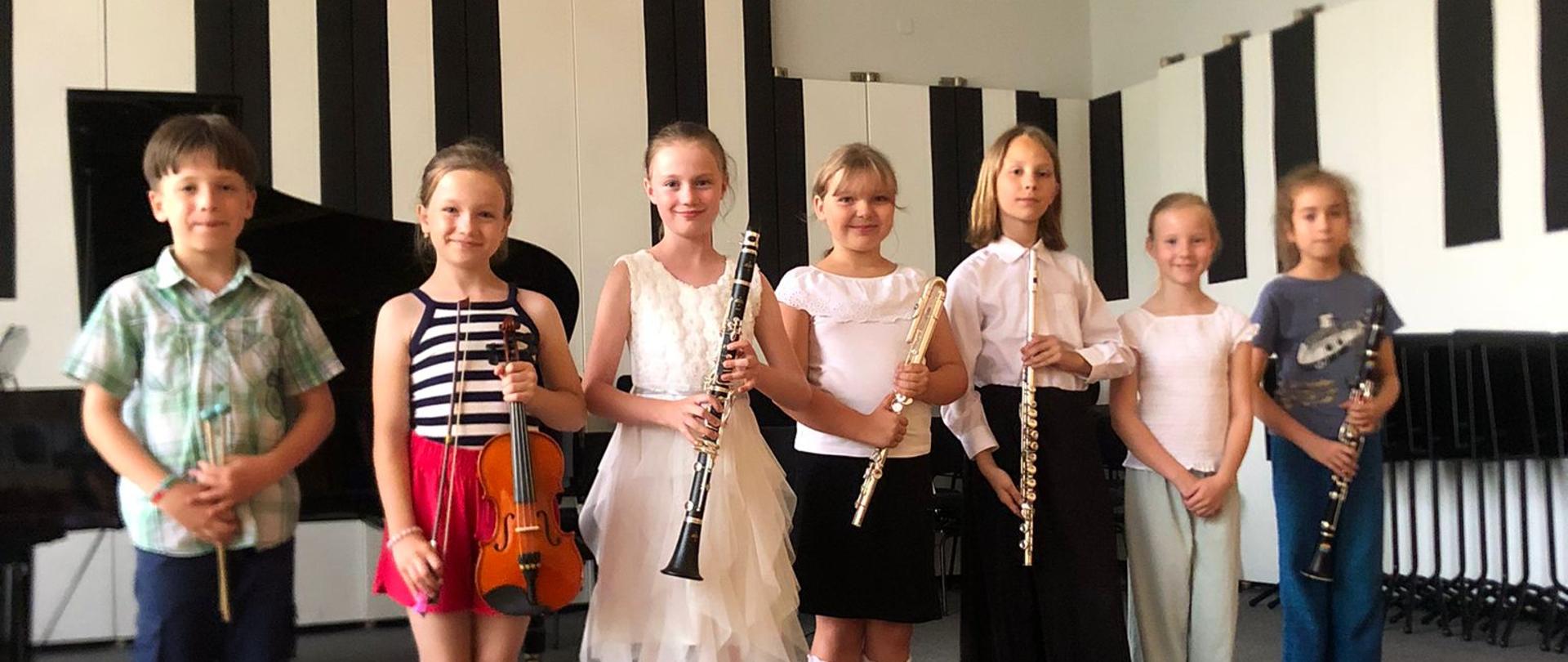 Wszyscy wykonawcy stoją na scenie ze swoimi instrumentami.
