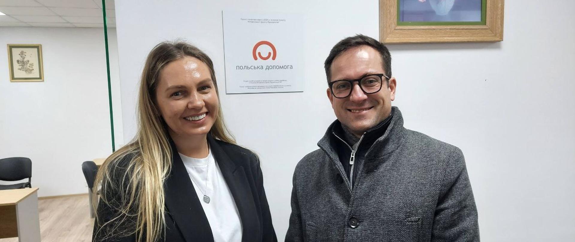 Zdjęcie przedstawia konsula Krzysztofa Łukjanowicza z KG Lwów oraz Tetianę Zbyrak, dyrektorkę Agencji Rozwoju Regionalnego Obwodu Iwanofrankiwskiego. W tle emblematy Polskiej pomocy i pokój przyjęć interesantów.