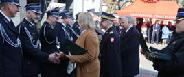 Komendant główny PSP wraz z panią minister klimatu wręczają promesy strażakom OSP