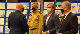 Funkcjonariusz Policji gratuluje strażakowi oraz innym partnerom projektu edukacyjnego. 