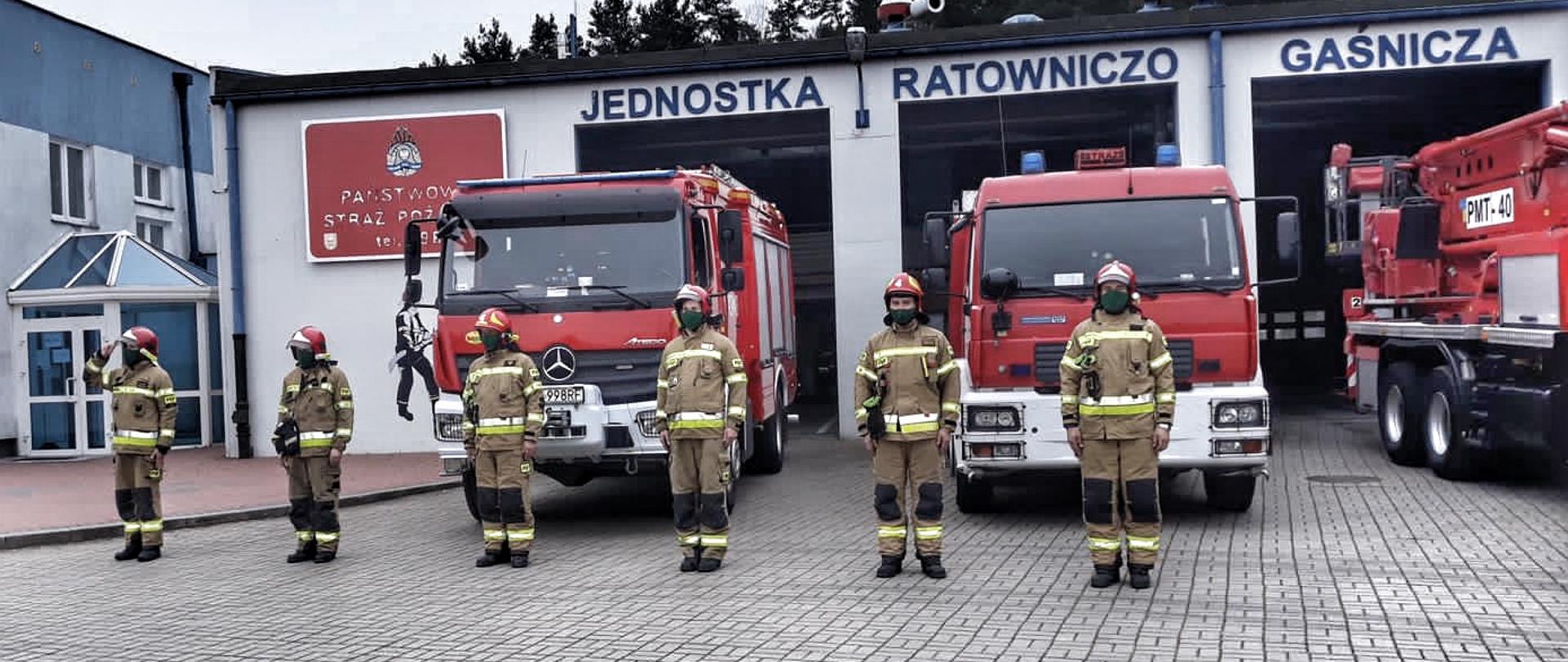Zmiana służbowa stoi przed samochodami pożarniczymi i śpiewa "Mazurka Dąbrowskiego".
