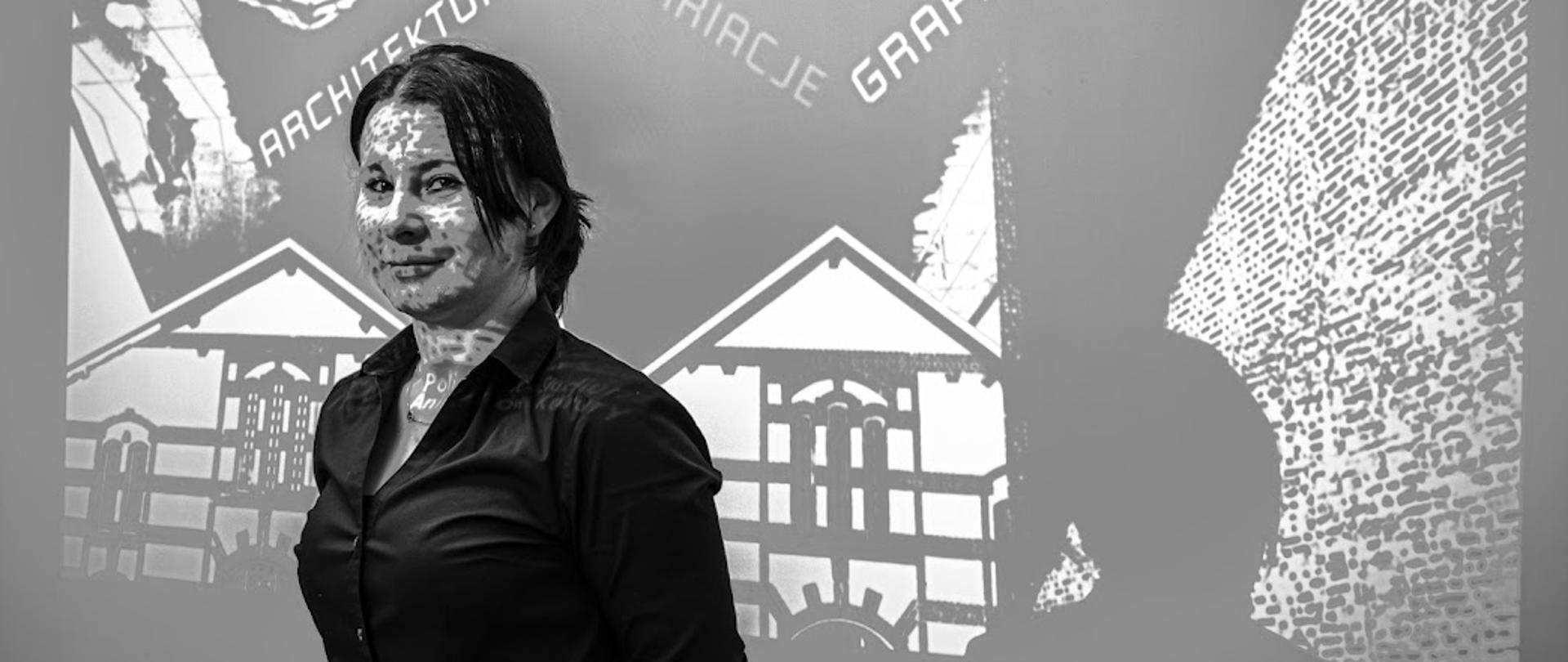 Zdjęcie w odcieniach szarości. Na zdjęciu jest słuchaczka, które stoi na tle szaro-białego zdjęcia.