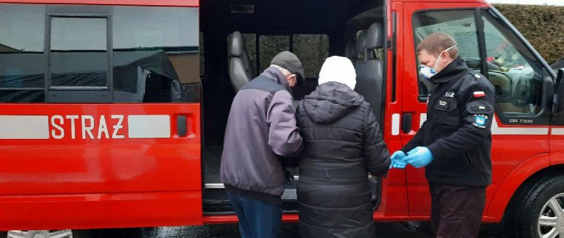 zdjęcie przedstawia strażaka OSP Żnin który pomaga starszej kobiecie wejść do samochodu 