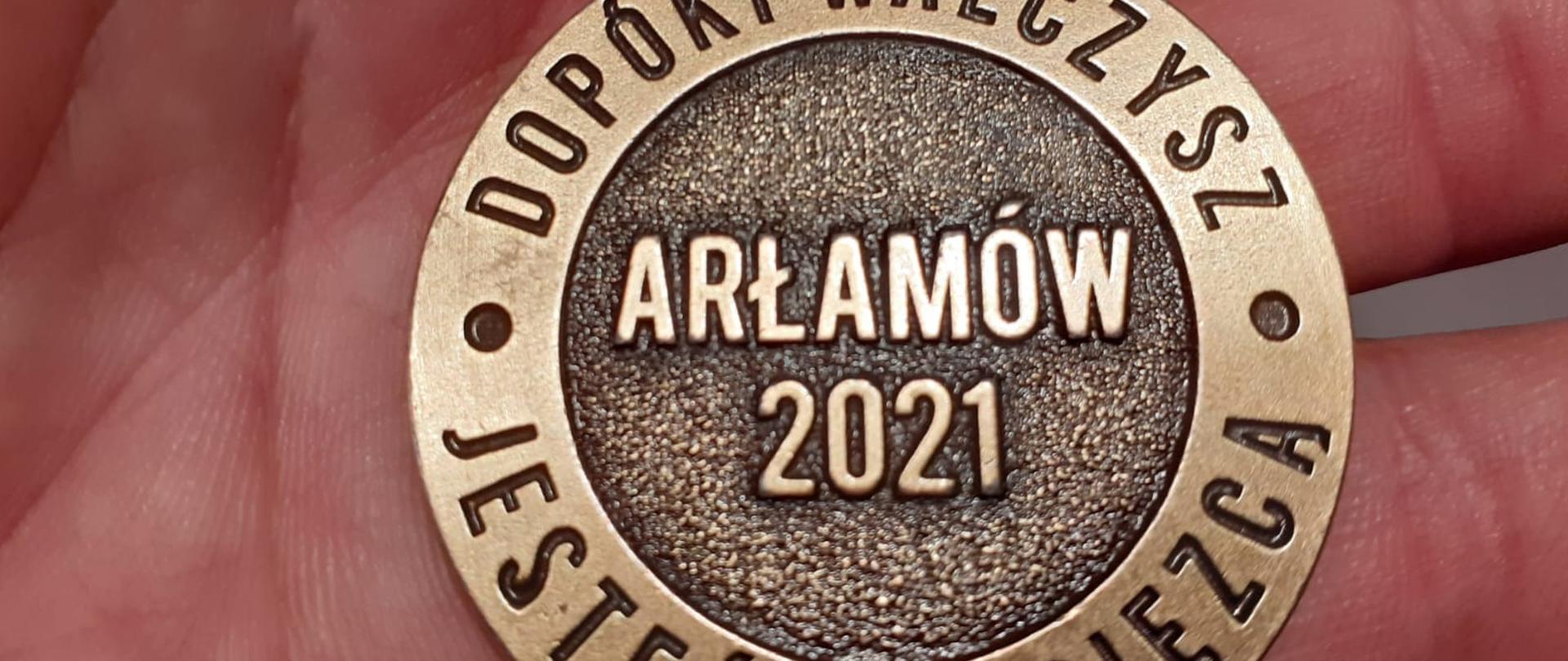 Medal z napisami położony na dłoni.