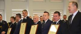 Strażacy w umundurowaniu z aktami włączenia do KSRG.