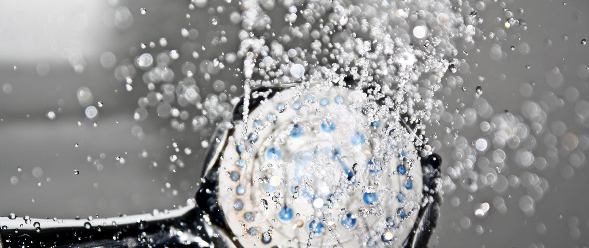 Zdjęcie ukazujące głowicę prysznica, z której wylatują krople wody